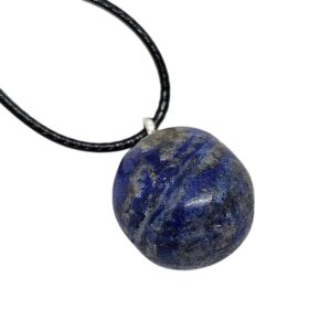 Lapislazuli Anhänger in tiefblauer Farbe mit natürlicher Struktur, an schwarzer Baumwollkordel hängend, auf hellem Hintergrund fotografiert.