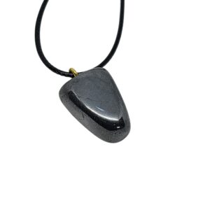 Hämatit Anhänger mit charakteristischem metallischem Glanz, an schwarzer Baumwollkordel hängend, in Geschenkbox präsentiert.